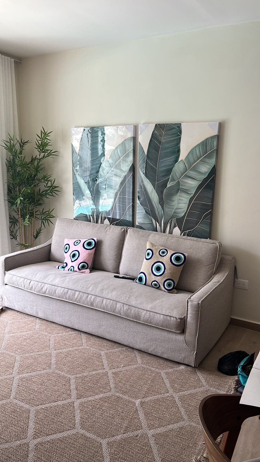 Light linen sofa with botanical art and a woven rug in a furnished living room